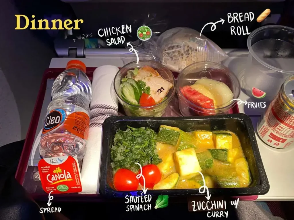 Qatar airways low calorie meal dinner consisting of Zucchini curry, spinach, side salad, fruit cup, bread roll and vegan spread