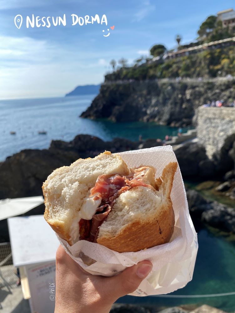 Sandwich with soft cheese and cured meats by the beach in Manarola, Cinque Terre